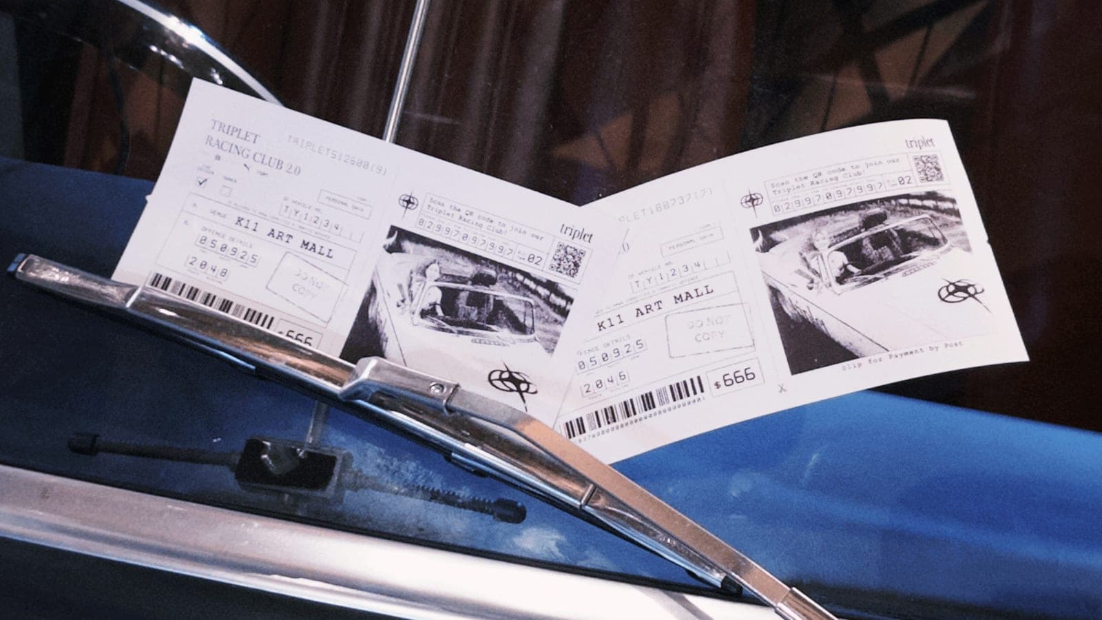 Two printed speeding-ticket photo slips resting on the convertible's bonnet.