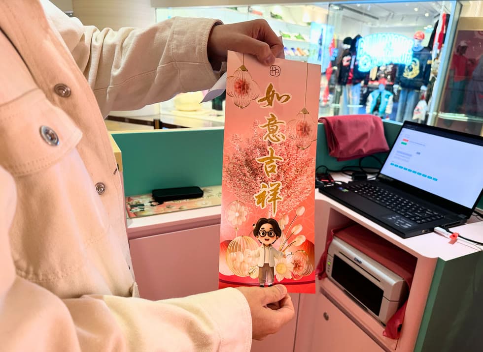 A guest holding a freshly printed personalised Fai Chun beside the booth printer.